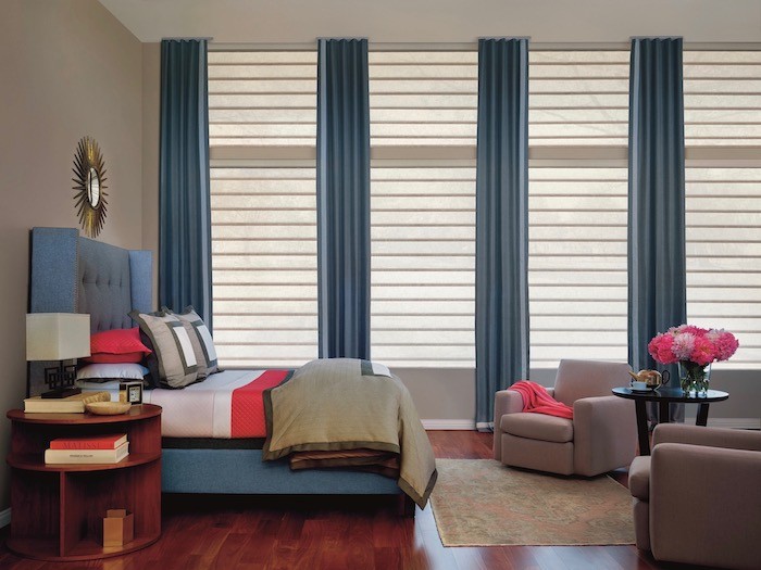 Bedroom with blue fabric headboard and matching floor to ceiling curtains